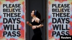 A person runs past posters with a message of hope, as the spread of the coronavirus disease (COVID-19) continues, in Manchester, Britain, April 12, 2020. 