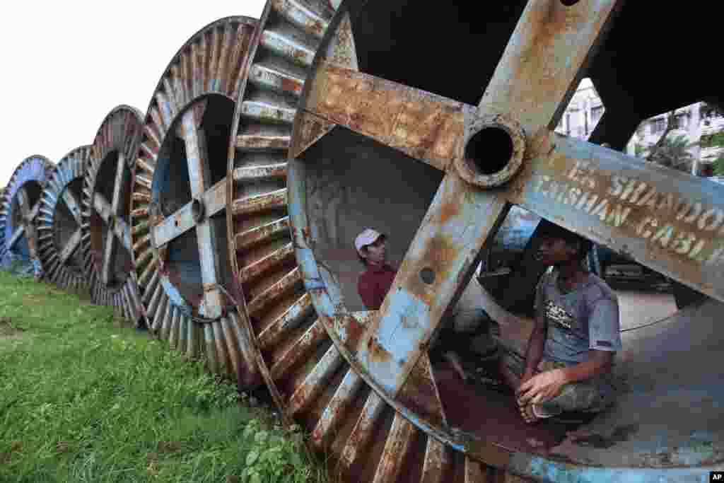 Bangladeshi rickshaw pullers rest inside a cable reeler in Dhaka.