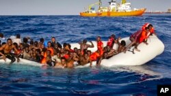 Para migran Afrika dengan perahu karet minta bantuan kapal untuk menolong mereka di perairan dekat pulau Lampedusa, Italia hari Minggu (17/4). Ratusan migran Afrika dilaporkan tenggelam pada 8 April lalu. 