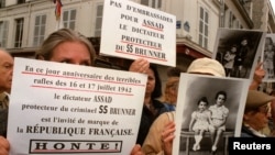 FILE - A few dozen members of Jewish organizations express outrage that Syrian President Hafez al-Assad, whom they accuse of sheltering convicted Nazi criminal Alois Brunner, was to be received by French President Chirac on the anniversary of a WWII round