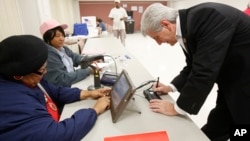 Poll workers Bertha Moses, left, and Florine Williams, check Mississippi Gov. Phil Bryant's driver's license as part of the voter ID procedure for anyone who casts a ballot, in a Jackson, Mississippi, precinct, Nov. 3, 2015.