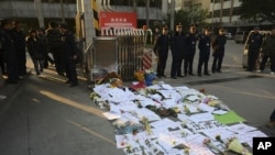Security guards stand near protest banners and flowers are laid outside the headquarters of Southern Weekly newspaper in Guangzhou, Guangdong province January 7, 2013. 