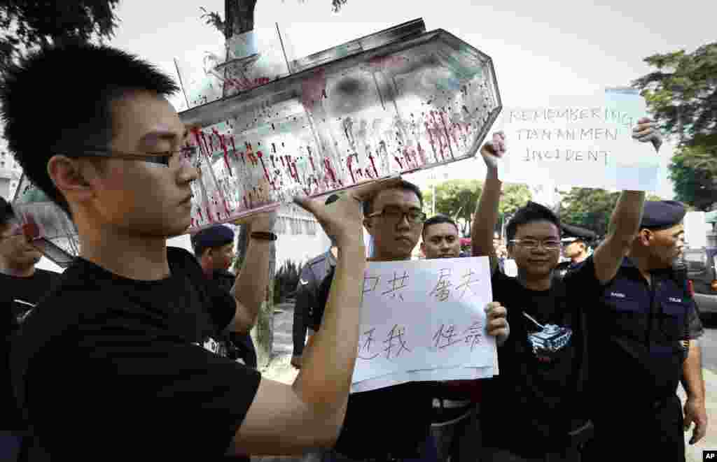 Seorang pemrotes membawa model tank berlapis cat merah yang melambangkan darah dalam aksi protes di depan Kedubes China di Kuala Lumpur, Malaysia (4/6).