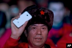 FILE - A fan of Xiaomi (China's Apple) smartphone holds up one of the phones during a product unveiling event of the Chinese company in Beijing.