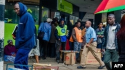 Residents walk in a street as others queue outside a bank in Harare, Nov. 15, 2017.
