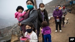 Neighbors wearing masks to curb the spread of the new coronavirus wait in a line for a free meal at the Villa Maria del Triunfo district of in Lima, Peru, Wednesday, June 17, 2020. The food was donated by a wealthy family and distributed to a poverty-str