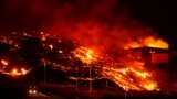 Lava burns buildings following the eruption of the Cumbre Vieja volcano in Tacande, Spain, October 9, 2021. 