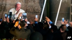 Faithful take photos with their mobile phones as Pope Francis departs from San Francisco Church aboard the Popemobile, in Quito, Ecuador, July 7, 2015. 