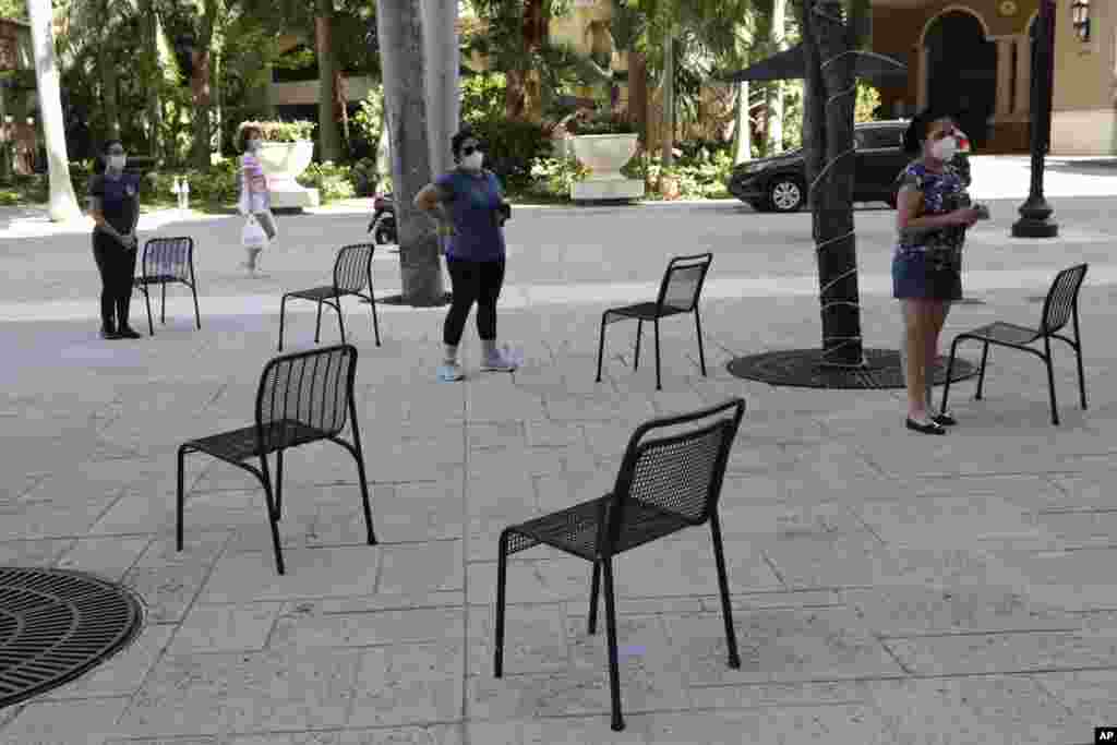 People practice social distancing as they wait in line for a complimentary meal at Someone's Son restaurant, during new coronavirus pandemic, Wednesday, April 22, 2020, in Coral Gables, Fla. (AP Photo/Lynne Sladky)