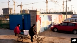 Workers ride a tricycle outside a construction site of a residential real estate project in Beijing, China, January 13, 2013.