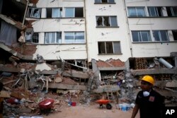 A rescue worker walks in front of an apartment building whose first four floors collapsed, in the Lindavista neighborhood of Mexico City, Sept. 20, 2017.