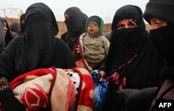 FILE - Syrian refugee women holding children are seen at Rukban camp, located in a no-man's-land on the border between Syria and Jordan, March 1, 2017.