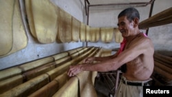 FILE- A man works inside a rubber factory at Raman district in the southern province of Yala, Thailand. Thailand's junta has approved $1.3 billion in rural subsidies, akin to the populist policies of the government it ousted, to appease disgruntled and po