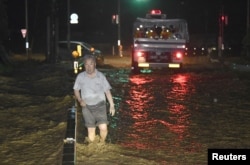 A man walks through a flooded street in Asakura, Fukuoka prefecture, Japan, in this photo taken by Kyodo, July 5, 2017.