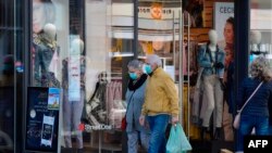 A woman and a man wearing face masks walk past a shop in Leipzig, eastern Germany