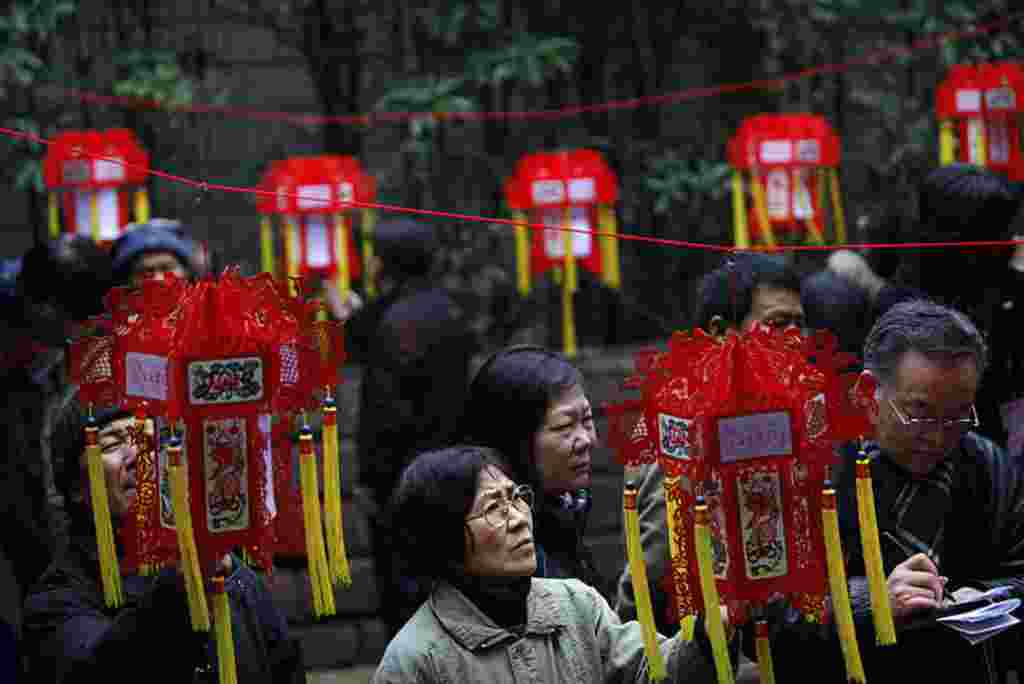 Para orangtua yang mencari jodoh bagi anak-anaknya membaca informasi mengenai lajang yang juga mencari jodoh, tertera di lentera-lentera merah pada sebuah acara hari Valentine di Taman Rakyat, di Shanghai, Tiongkok, 14 Februari (Reuters).