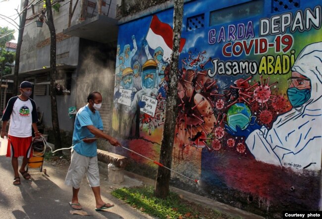 Warga menyemprotkan cairan disinfektan untuk mencegah penyebaran COVID-19 di salah satu area lingkungan di Tangerang, pada 15 Mei 2020. (Foto: Antara Foto/Muhammad Iqbal via Reuters)
