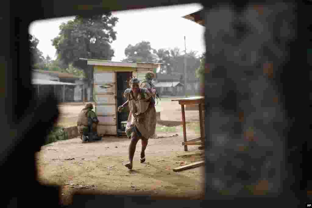 Seorang perempuan berlindung dari serentetan tembakan senjata di distrik bernama Miskin di Bangui, Republik Afrika Tengah. Pertempuran sengit berlangsung di daerah ini antara milisi Muslim dengan pasukan Burundi.