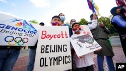 FILE - Children hold signs during a demonstration by a coalition representing Tibetans, Uyghurs, Southern Mongolians, Hong Kongers, Taiwanese and Chinese rights activists in Boston, June 23, 2021.