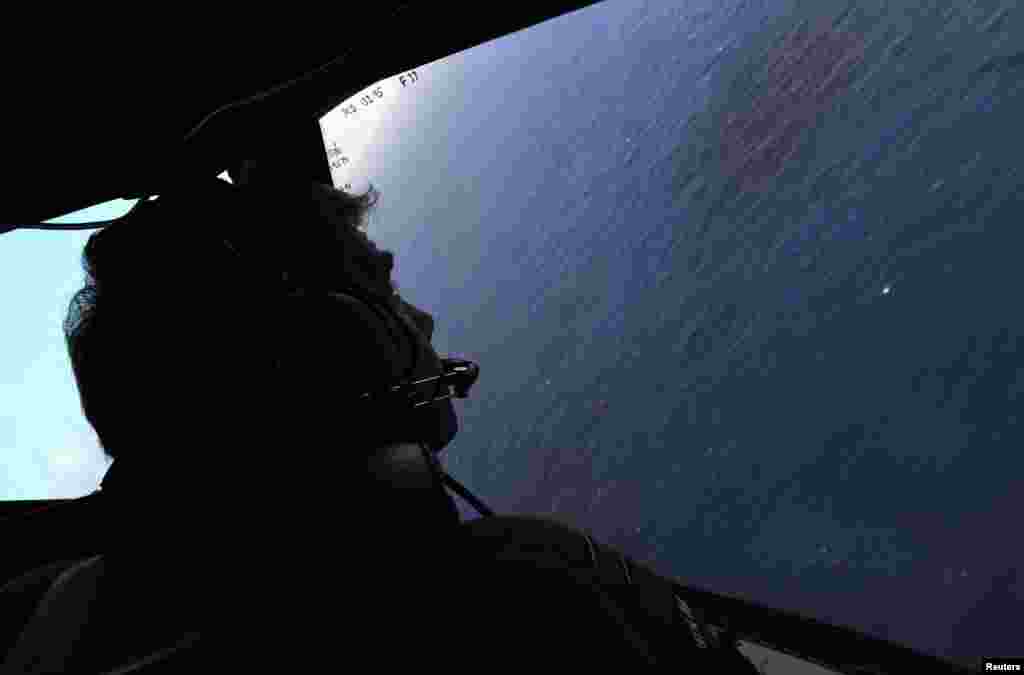Co-pilot and Squadron Leader Brett McKenzie looks from the cockpit of a Royal New Zealand Air Force aircraft as they fly over the southern Indian Ocean, to continue the search for Flight MH370, April 13, 2014.