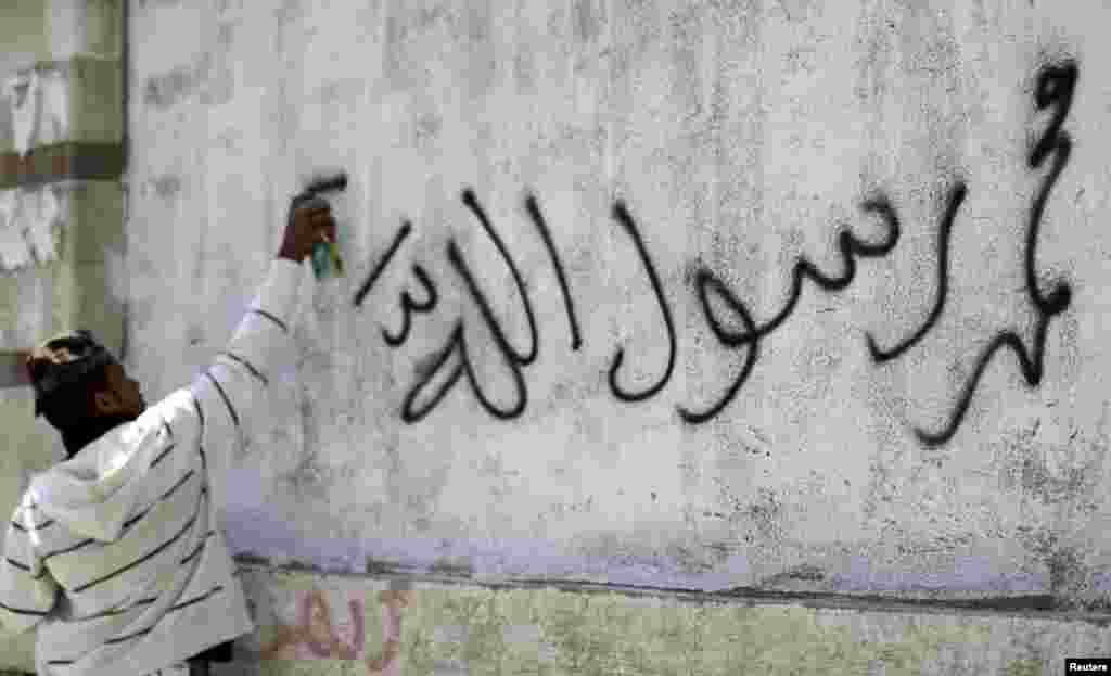 Seorang demonstran mencoreti dinding sebagai bagian protes di Kedutaan Besar AS di Sanaa (13/9). (Reuters)