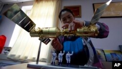 A vendor assembles a model showing the Shenzhou 9 space craft docked with the Tiangong 1 space module with three astronauts, June 17, 2012.