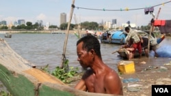 Matt Zen repairs a fishing boat on the river bank in Sangkat Chroy Changva, Phnom Penh, June 5, 2021. (Vicheika Kann/VOA)
