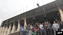 Thanh niên Libya chụp ảnh lưu niệm ở lối vào căn nhà bị đốt của ông Moammar Ghadafi bên trong căn cứ quân sự Al-Katiba tại Benghazi, Libya, 27/2/2011