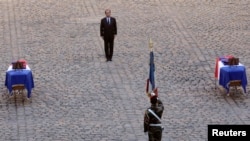 French President Francois Hollande pays his respects in front of the two flag-draped coffins bearing the French soldiers who died last week in the Central African Republic, during a ceremony at the Invalides, in Paris, Dec. 16, 2013. 
