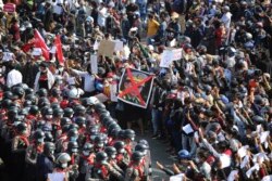 Protesters flash three fingered salutes while holding an image with an X mark on the face of Myanmar Commander-in-Chief Senior General Min Aung Hlaing in Naypyitaw on February 8, 2021.