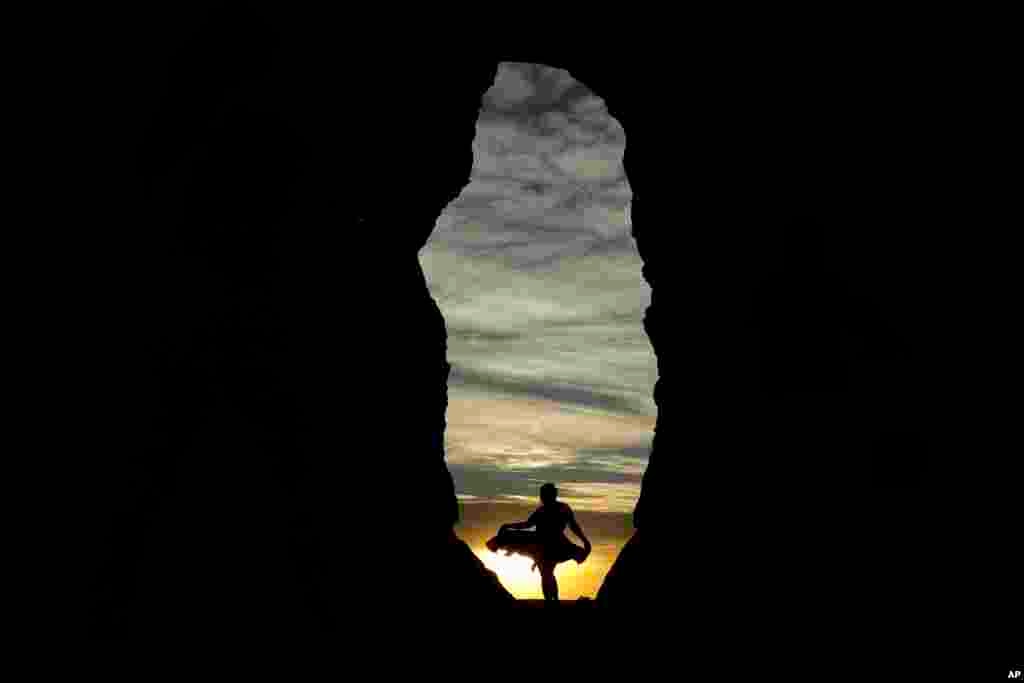 A woman is seen against the setting sun in Monument Rocks, May 20, 2020, south of Oakley, Kansas.