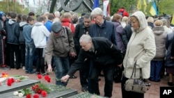 People lay flowers at a memorial bearing the names of victims of the Chernobyl nuclear accident, during a commemoration of the disaster's 30th anniversary, in Kyiv, Ukraine, April 26, 2016.