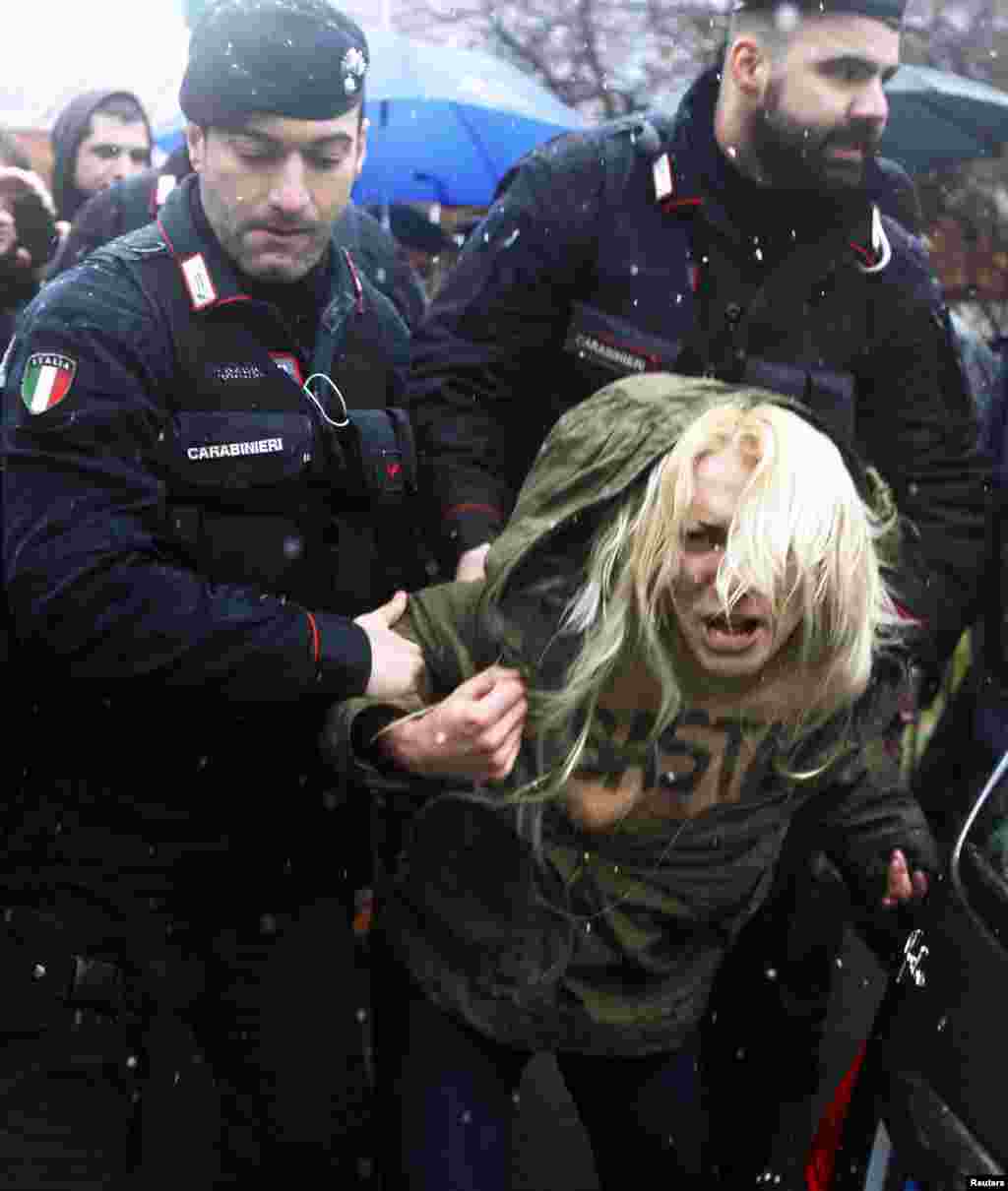 Carabinieri stop a protester from the women&#39;s rights organization Femen outside the polling station where former Prime Minister Silvio Berlusconi cast his vote in Milan, Italy, Feb. 24, 2013. 