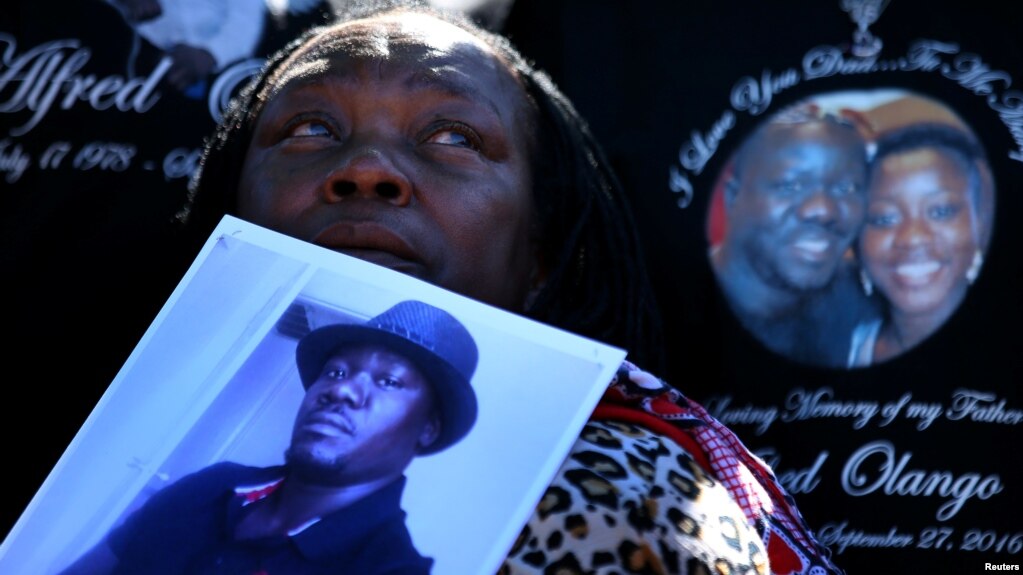 FILE - A woman holds a picture of Alfred Olango as she listens to speeches during an Oct. 1, 2016, rally and march to protest the fatal police shooting of the Ugandan immigrant in El Cajon, California, four days earlier.