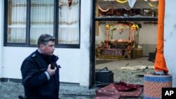 FILE - In this April 16, 2016, photo, a police officer walks in front of a Sikh temple after an explosion near it injured three people and damaged the structure, in the western German city of Essen.