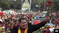 Venezuela's President Hugo Chavez holds up flowers thrown by supporters during his caravan from Miraflores presidential palace to the airport in Caracas, February 24, 2012.