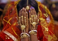 Seorang pengantin perempuan menutupi wajahnya saat dia menunggu untuk mengambil sumpah pernikahannya pada upacara pernikahan massal di Desa Bahirkhand, utara Kolkata, 8 Februari 2015. (Foto: Reuters)