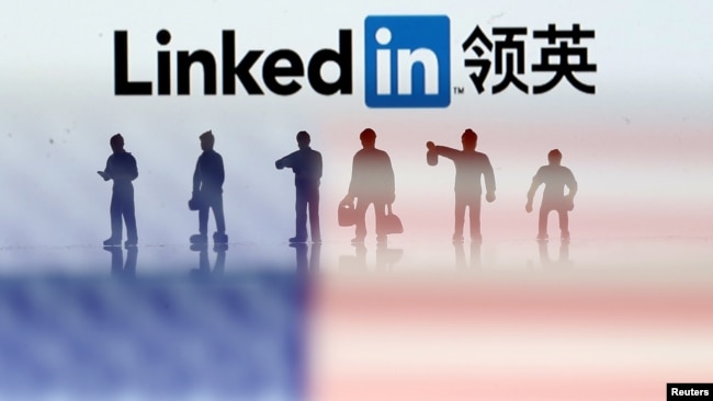 FILE - Small toy figures are seen between displayed U.S. flag and Linkedin logo in this illustration picture.