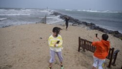 Orang-orang menyaksikan ombak saat mereka berdiri di pantai menjelang Badai Tropis Henri di Montauk, Long Island pada 22 Agustus 2021.