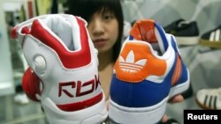 Một người bán hàng trình bày những chiếc giày của Reebok và Adidas ở Đài Bắc. Công ty Pou Yuen của Đài Loan, chuyên sản xuất giày dép, bị phán quyết phải trả tiền bồi thường cho các công nhân của họ sau khi đóng cửa nhà máy ở Campuchia.