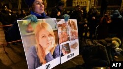 In this Feb. 4, 2019 photo, an activist holds a portrait of Kateryna Gandzyuk along with photos showing her traumas after the July 2018 acid attack that eventually killed the Ukrainian anti-corruption campaigner.