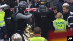 Hooded police officers detain a man in Saint-Denis, near Paris, after a raid on an apartment where the suspected mastermind of last week's terror attacks in the French capital was believed to have been holed up, Nov. 18, 2015.