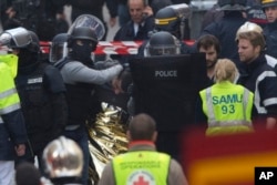 Hooded police officers detain a man in Saint-Denis, near Paris, after a raid on an apartment where the suspected mastermind of last week's terror attacks in the French capital was believed to have been holed up, Nov. 18, 2015.