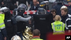 Hooded police officers detain a man in Saint-Denis, near Paris, after a raid on an apartment where the suspected mastermind of last week's terror attacks in the French capital was believed to have been holed up, Nov. 18, 2015.