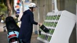 FILE - A man swaps batteries at a Gogoro GoStation unit in Taipei on March 26, 2018.