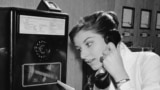 As coins slide down before her eyes, a German woman uses a new long distance dial telephone for public booths, July 17, 1957. (AP Photo)