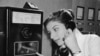 As coins slide down before her eyes, a German woman uses a new long distance dial telephone for public booths, July 17,1957.(AP Photo)