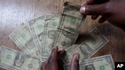 An unidentified man shows dirty one dollar notes before washing them in Harare, Zimbabwe. The washing machine cycle takes about 45 minutes and George Washington comes out much cleaner than before in Zimbabwe-style.