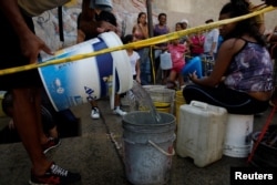 Venezuelans line up to collect water from an underground water main in Caracas, Venezuela, April 1, 2019.