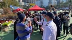 香港支聯會主席李卓人（左）就維園年宵攤檔被終止合約，一度與到場進行清場行動的食環署職員發生爭執。(美國之音 湯惠芸拍攝)